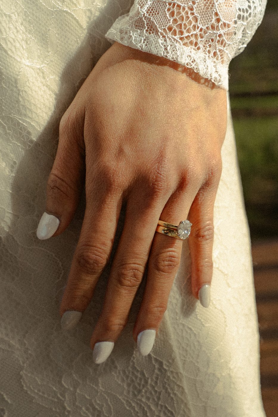 A bride's hand resting on lace, the ring catching afternoon light
